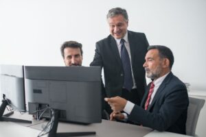 Three business colleagues in suits happily collaborating at the office.